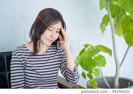 一個在電腦前工作的女人在客廳裡抱著頭 99144203