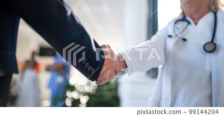 Close-up of handshake of doctor and business woman. 99144204