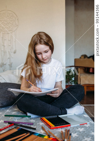 The girl after school plays at home, draws with pencils and felt-tip pens The girl after school plays at home, draws with pencils and felt-tip pens 99144366