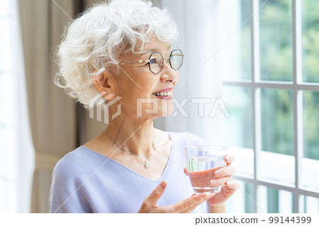Senior woman relaxing by the window Senior woman relaxing by the window 99144399