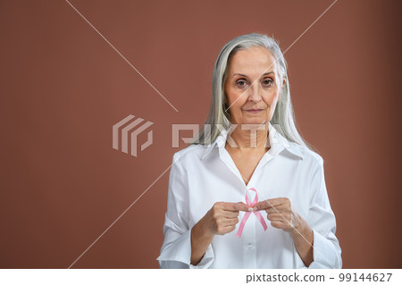 Senior woman holding pink bow. Breast cancer awareness concept. 99144627