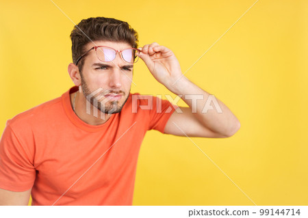 Caucasian man taking off her glasses to see far away Caucasian man taking off her glasses to see far away 99144714