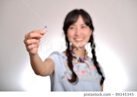 Portrait of beautiful young asian woman in denim dress holding engagement ring on white background Portrait of beautiful young asian woman in denim dress holding engagement ring on white background 99145345