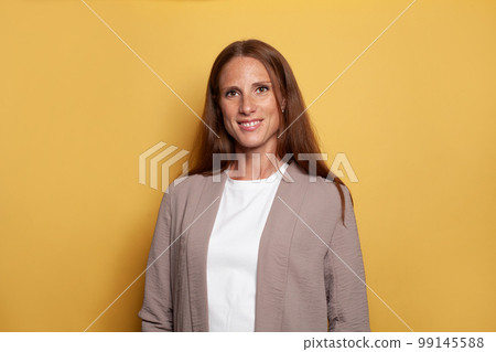 Elegant confident smiling woman in formal wear looking at camera on yellow background 99145588
