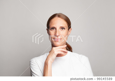 Healthy mature female face close up. Pretty mid adult woman with fresh healthy skin with freckles 99145589