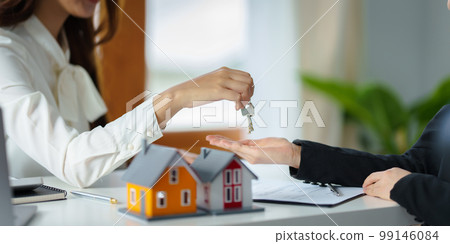 The real estate agent or agency giving house key to customer after signing agreement contract. Property concept. The real estate agent or agency giving house key to customer after signing agreement contract. Property concept. 99146084