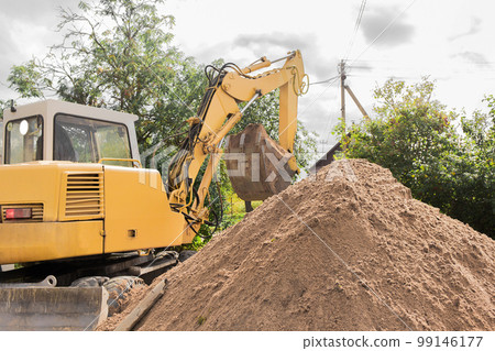 Hydraulic piston system excavator with a bucket unloads a large pile of land on an industrial site. Excavation construction work 99146177