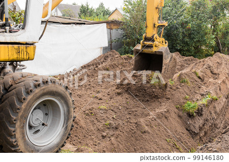 An excavator bucket digs the ground in an industrial area. Excavation construction work An excavator bucket digs the ground in an industrial area. Excavation construction work 99146180