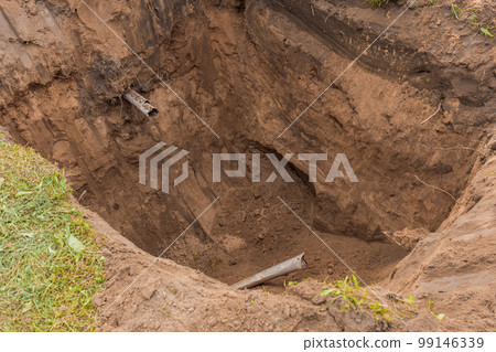 Large deep pit in the ground after digging an excavator sewer pipe in an industrial area Large deep pit in the ground after digging an excavator sewer pipe in an industrial area 99146339