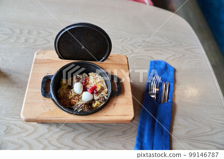 Traditional Uzbek cuisine. Pilaf with beef in a cast-iron pan cauldron. Background image. Copy space, selective focus. High quality photo 99146787