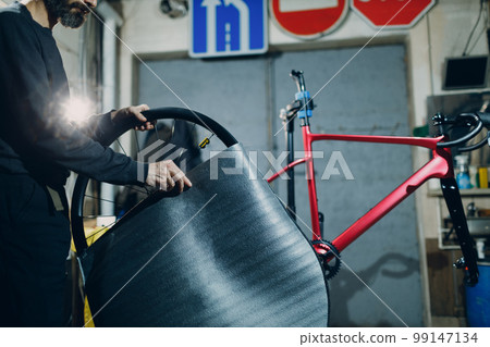Mechanic repairman assembling wheel custom bicycle in workshop Mechanic repairman assembling wheel custom bicycle in workshop 99147134