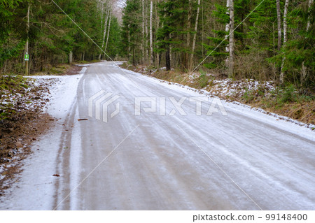 Forest road in spring. The road is icy, slippery. pass through a thick coniferous forest. Latvia Forest road in spring. The road is icy, slippery. pass through a thick coniferous forest. Latvia 99148400