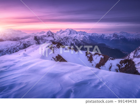 Snow covered mountains and purple sky with clouds at sunset 99149438