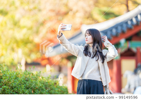 Woman taking a selfie with a smartphone while traveling 99149596