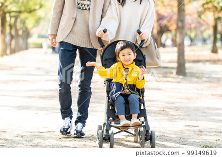 Young family taking a walk with a stroller Young family taking a walk with a stroller 99149619