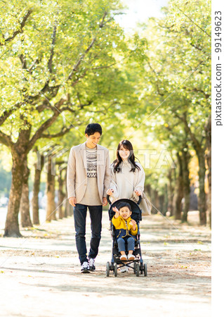 Young family taking a walk with a stroller Young family taking a walk with a stroller 99149623