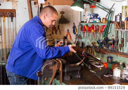 Gunsmith performing checkout of single-barrelled shotgun in weapons workshop 99151529