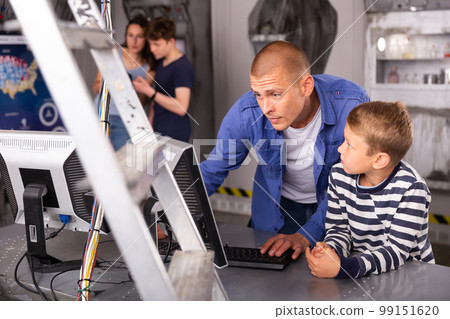 Portrait of a father and son in front of a computer in the quest room Portrait of a father and son in front of a computer in the quest room 99151620