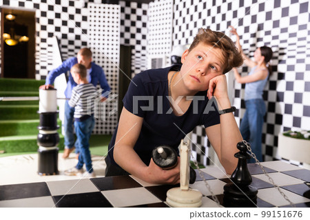 Teenager solving conundrum in quest room stylized under chessboard 99151676