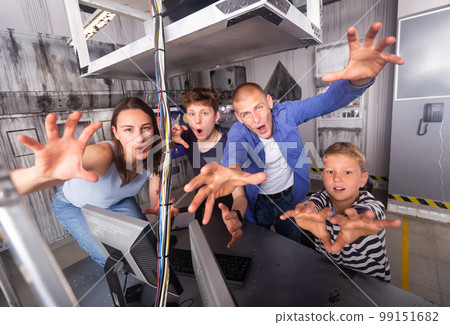 Family frighteningly looking and holding out hands in quest room 99151682