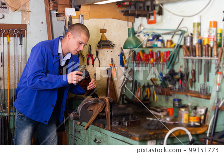 Gunsmith repairs butt of a shotgun in weapons workshop Gunsmith repairs butt of a shotgun in weapons workshop 99151773