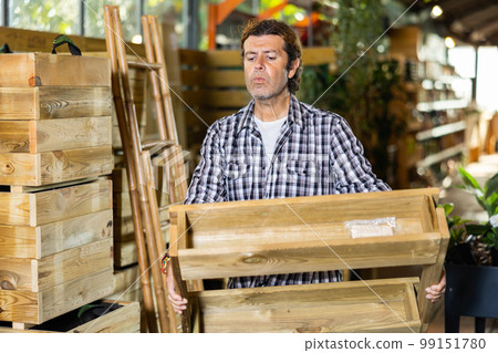European gardener examines a rack of pallets for planting flower sprouts European gardener examines a rack of pallets for planting flower sprouts 99151780
