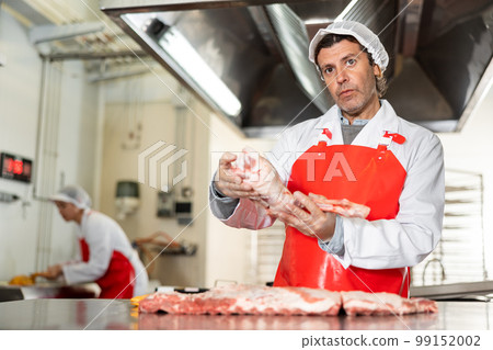 Male seller demonstration quality porks in butcher shop Male seller demonstration quality porks in butcher shop 99152002