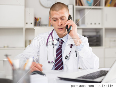 Male doctor consults a patient on the phone in the office 99152116