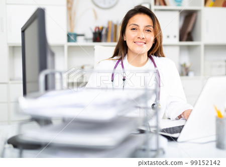 Woman doctor sitting at workplace with computer in office Woman doctor sitting at workplace with computer in office 99152142