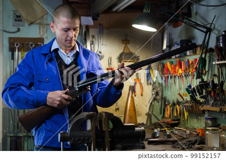 Double-barreled hunting rifle in hands of gunsmith in weapons workshop Double-barreled hunting rifle in hands of gunsmith in weapons workshop 99152157