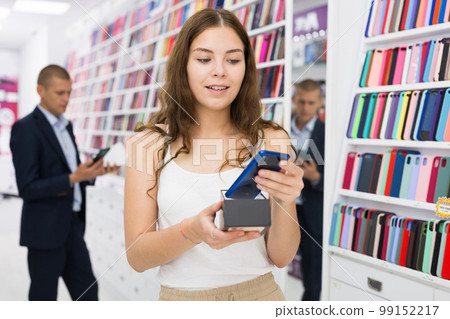 Young woman choosing phone in consumer electronics store Young woman choosing phone in consumer electronics store 99152217