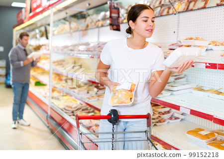 Woman buys raw chicken thighs in the meat department of supermarket Woman buys raw chicken thighs in the meat department of supermarket 99152218