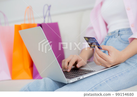 Closeup hands of woman sitting on sofa using laptop computer shopping online with credit card. Closeup hands of woman sitting on sofa using laptop computer shopping online with credit card. 99154680