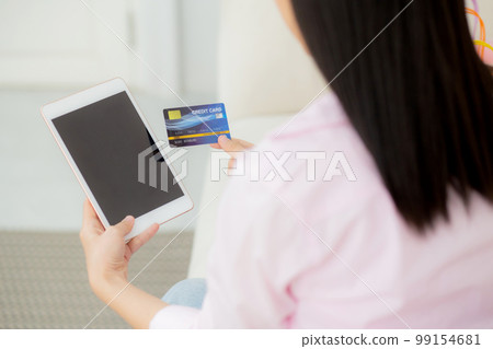 Young asian woman holding credit card shopping online with tablet computer blank. 99154681