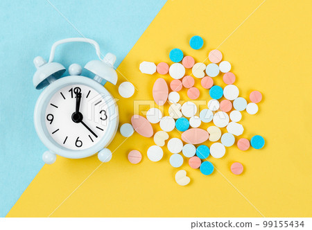 White alarm clock and many drug on a yellow background. Taking medicine at the right time concepts. 99155434