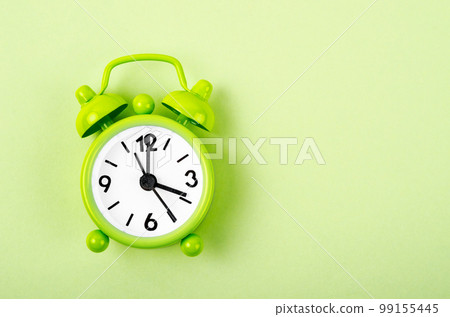 The Green alarm clock on green colour background. The Green alarm clock on green colour background. 99155445