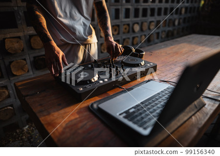 DJ playing music,Man using mixing desk at party out in the evening DJ playing music,Man using mixing desk at party out in the evening 99156340