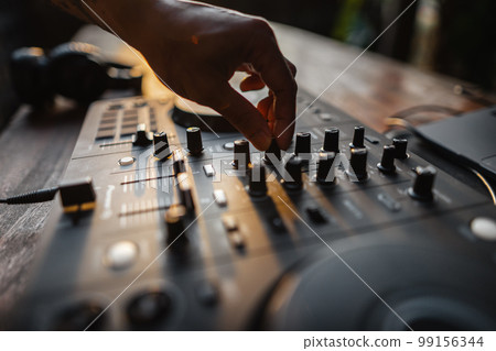 DJ playing music,Man using mixing desk at party out in the evening DJ playing music,Man using mixing desk at party out in the evening 99156344