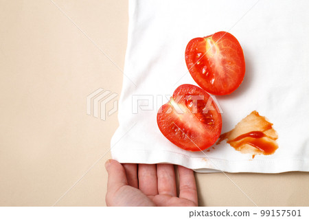 womans hand hold white shirt clothes with Tomatoes and ketchup stain 99157501