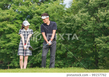 Male and female golfers giving golf lessons at a golf course (round lesson) 99157782