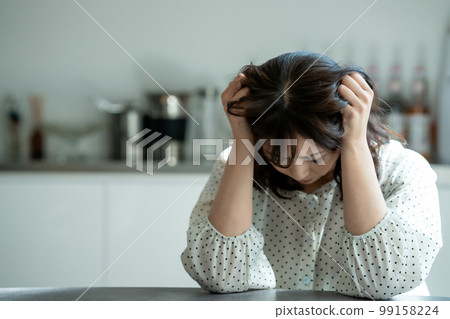 Middle-aged woman worried in the kitchen Middle-aged woman worried in the kitchen 99158224