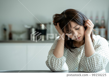Middle-aged woman worried in the kitchen Middle-aged woman worried in the kitchen 99158225