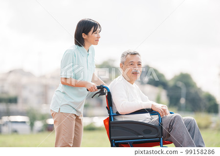 Caregiver and senior/Elderly man and helper walking in a wheelchair 99158286
