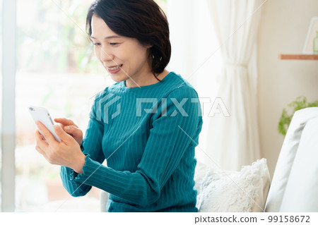 玩智能手機遊戲的中年婦女 99158672