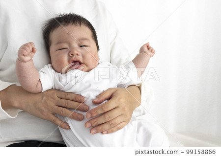 A crying baby being held by his mother on his lap (0 years and 2 months, Japanese, boy) 99158866
