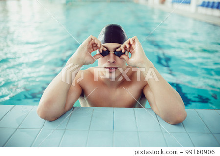 portrait of handsome professional swimmer on edge of the swimming pool. Sport concept  99160906