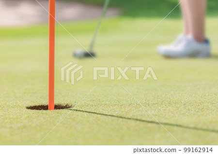 女高爾夫球手即將使用推桿在高爾夫球場上的杯子中進洞 99162914