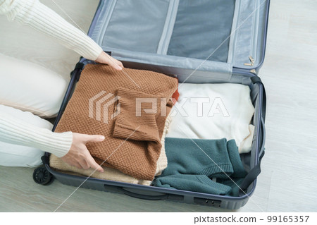 Woman hand packing her winter clothes in luggage. Time to travel, trip, Relax, spring or autumn or winter season and vacation concepts 99165357