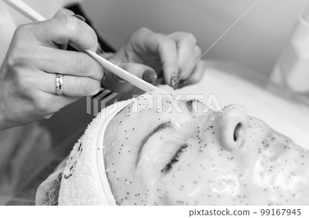 A cosmetologist removes a moisturizing sheet mask on a woman's face, cosmetology procedures. A cosmetologist removes a moisturizing sheet mask on a woman's face, cosmetology procedures. 99167945