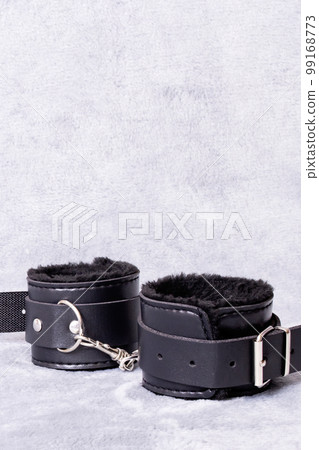 Black leather handcuffs on a gray background Black leather handcuffs on a gray background 99168773